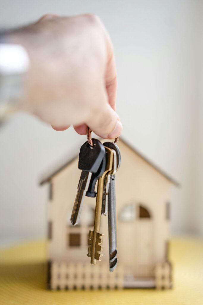 keys being held in front of a cardboard cutout house